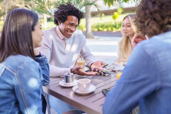 Multi-ethnic friends meeting up over coffee and juice at outside table