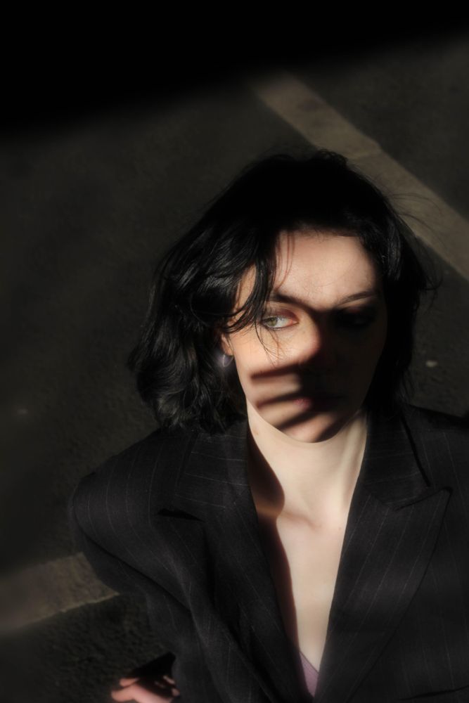 Portrait of woman in dark blazer with shadow of hand on her face