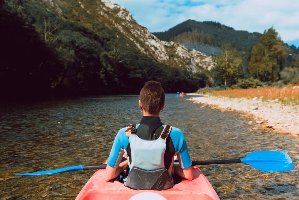 Female kayaking with paddle in raised hands