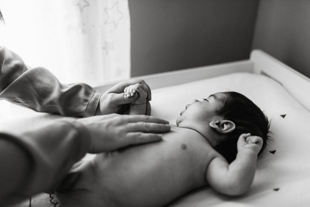 Crop mother playing with newborn baby boy