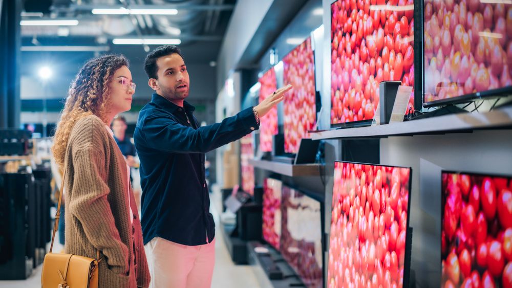 Customers Deliberate Over Television Options in Contemporary Shop