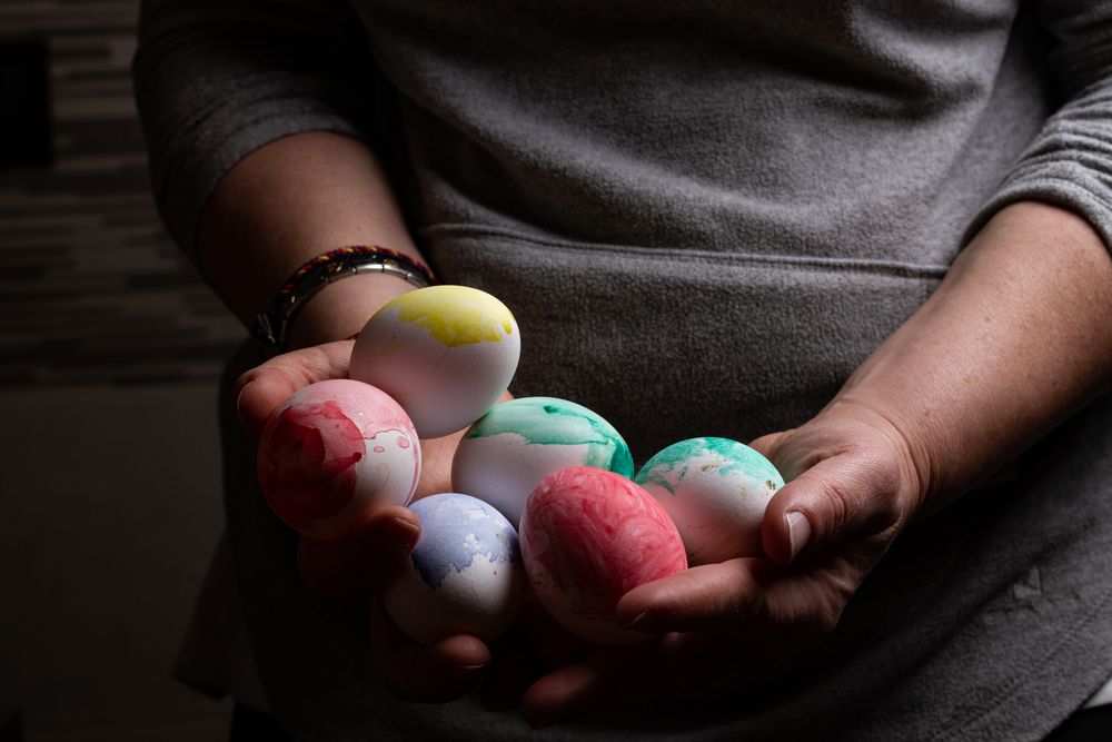 Woman holding many Easter eggs in darkness