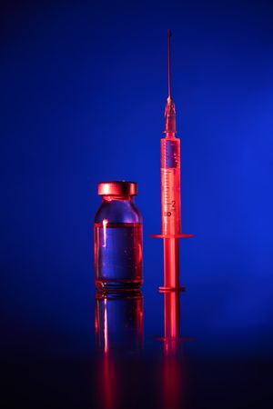 Vial and syringe with vaccine in dark room