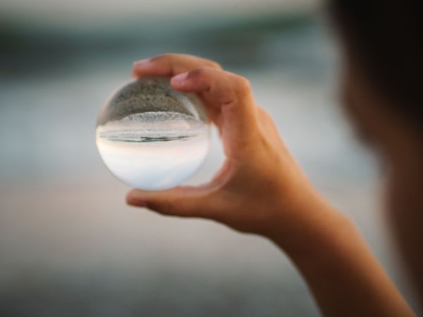Girl playing with glass ball on seaside
