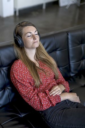 Woman at home sitting on couch wearing headphones with eyes closed