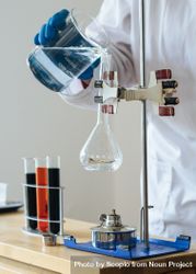 Cropped image of person pouring liquid into heated flask in chemistry lab 41vWjb