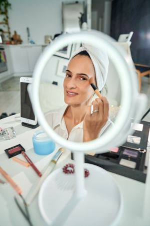 Smiling woman applying foundation on face