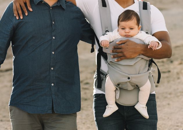 Unrecognizable diverse men walking with baby on nature
