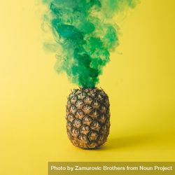 Pineapple with green smoke on bright yellow background 48g3v5