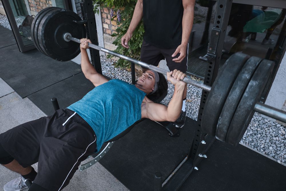 man lifting barbell with trainer