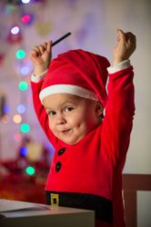 Cute kid in Santa costume with raised arms
