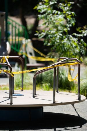 Closed caution signal tape around merry-go-round at city park