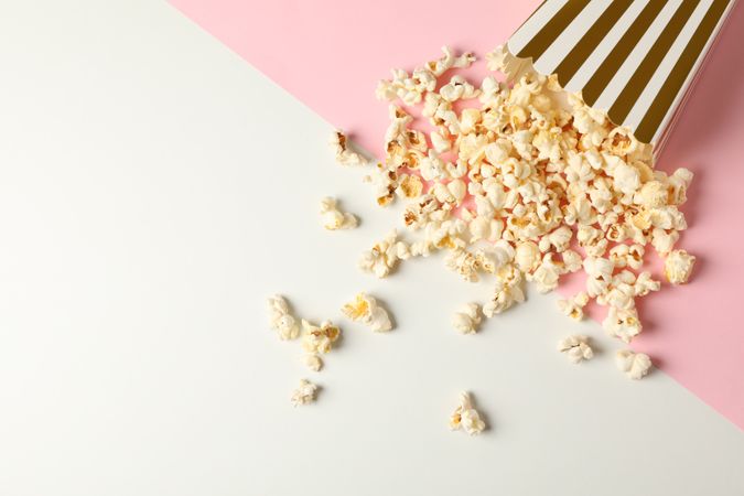 Flat lay composition with striped box and popcorn on color background