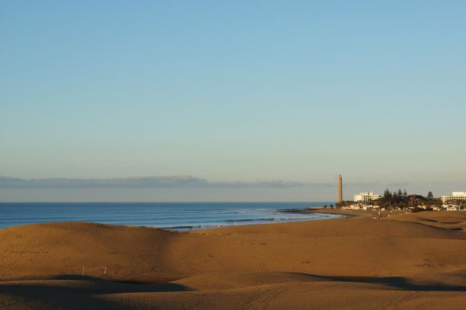 Sunny beach at exotic seashore with distant town