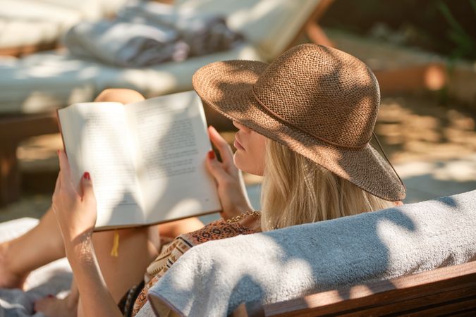 Stylish woman reading book in resort