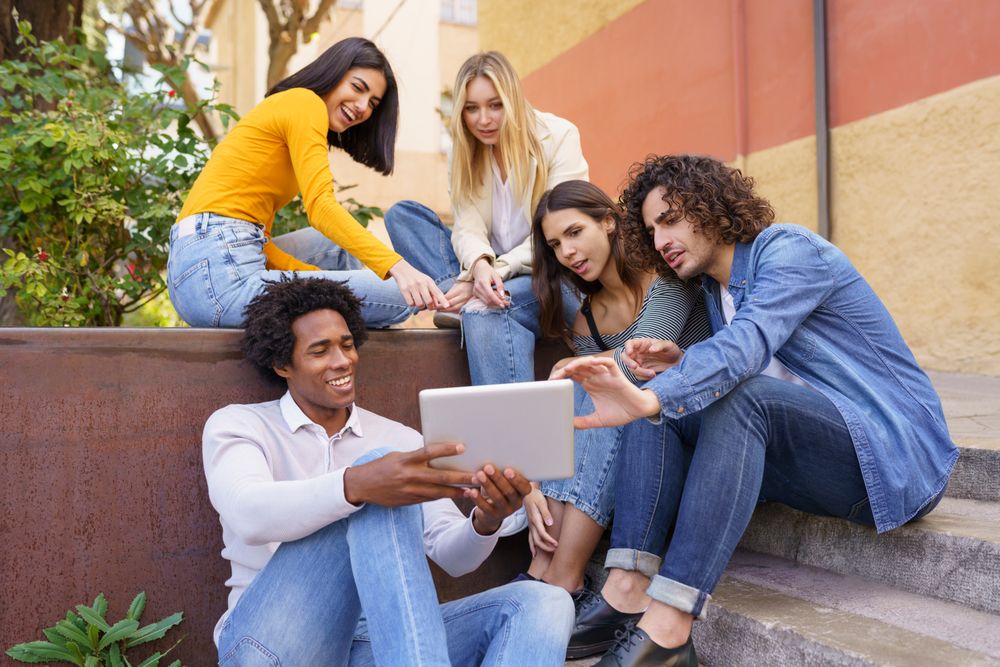 Friends gathered around a digital tablet outside