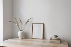Cozy Scandinavian interior with vase with dry grass bouquet on old books with cup of tea