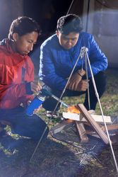 Two Young Asian Male Lighting a Campfire at a Camping Site