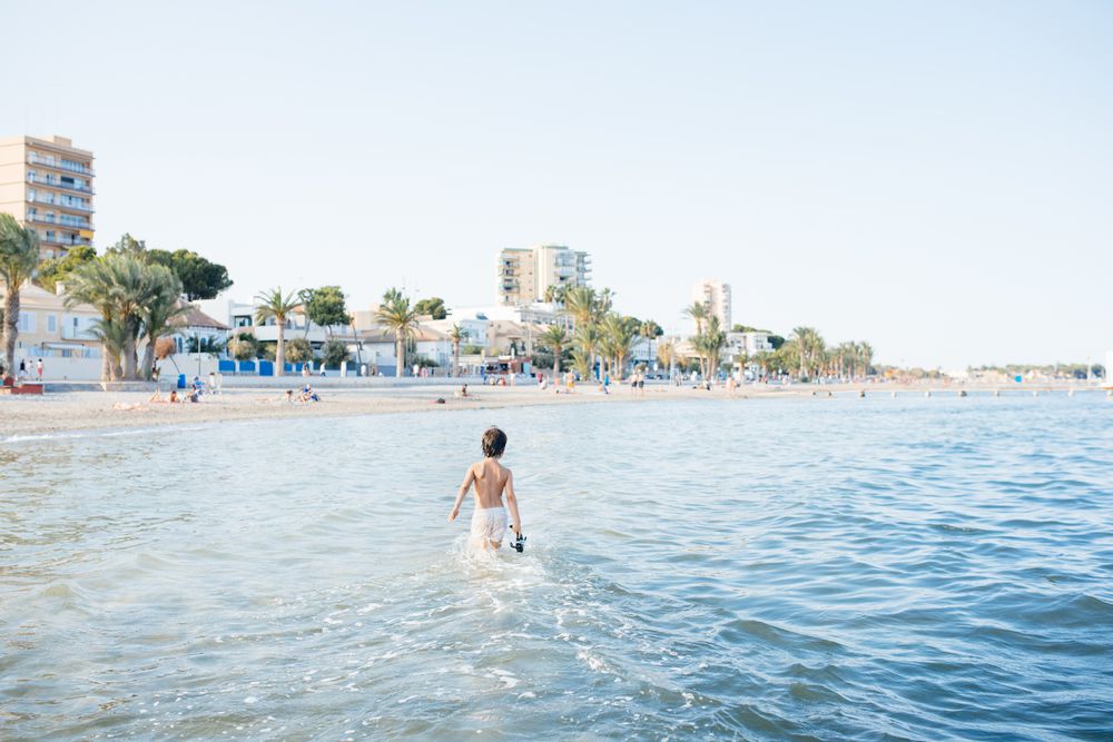 Boy walking in blue water of resort sea