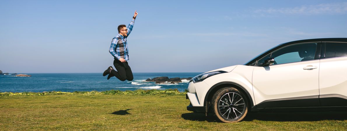 Young man jumping happy with car
