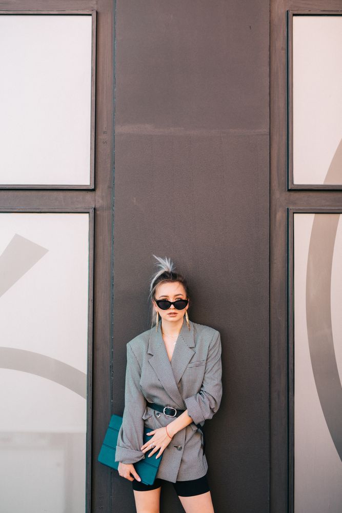 Stylish businesswoman with laptop leaning on wall