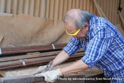 Asian male carpenter working on a wooden panel in the shop 5r99wZ