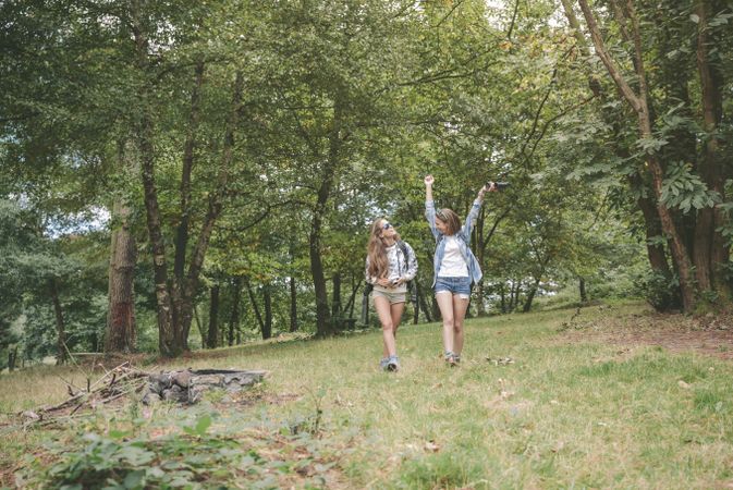 Female hiker raising arms and enjoying forest with friend
