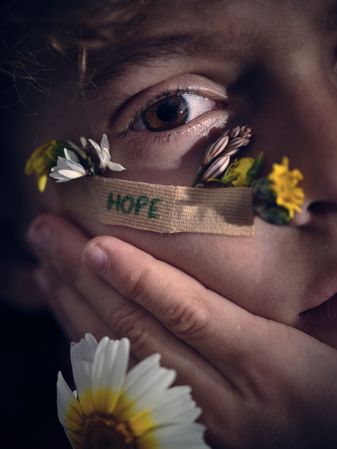 Crop boy with attached flowers under eye