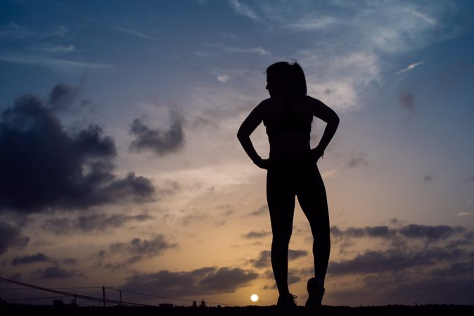 Stretching woman and sky with clouds at sunset