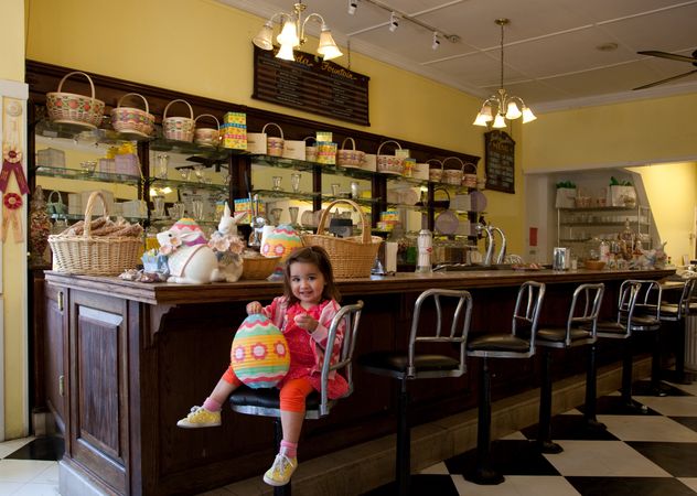 Young girl with Easter egg paper lantern sitting on stool at candy store in Mobile, AL