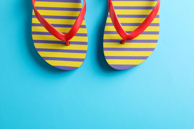 Flip flops on color background, space for text. Summer vacation backdrop