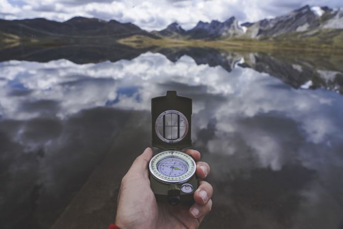 Crop hand with compass near lake
