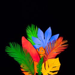 Neon tropical leaves layout in vivid  fluorescent colors on dark background