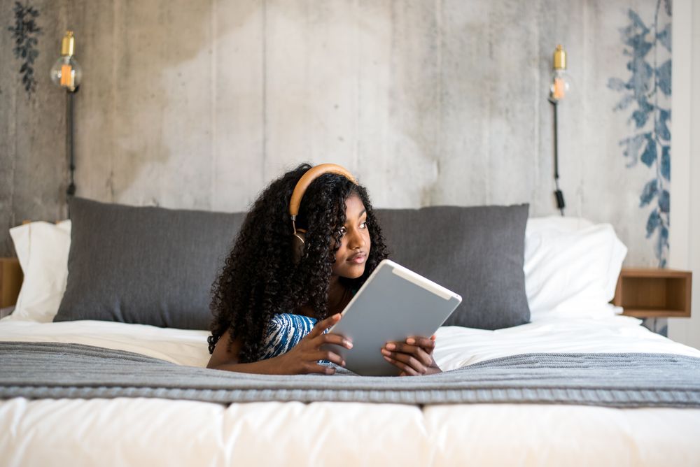 Black girl using tablet in bed
