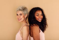 Two female friends standing back to back in studio shoot