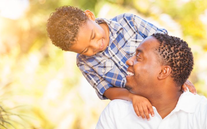 Young Black Son Smiling At Father Outdoors