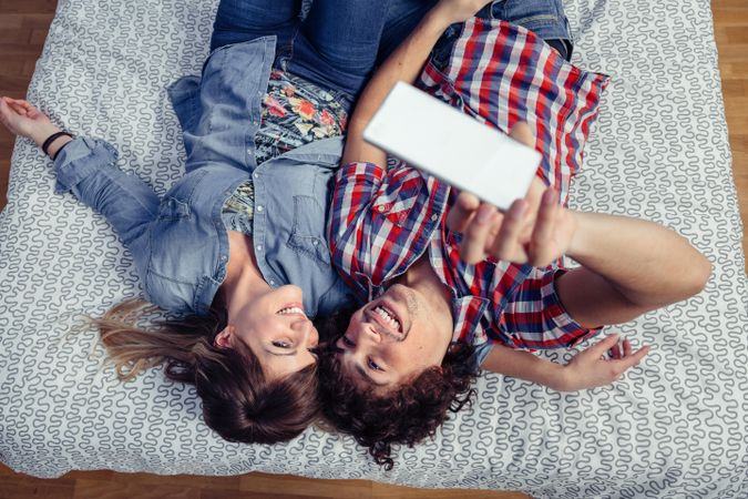 Couple in love taking selfie with smartphone on bed