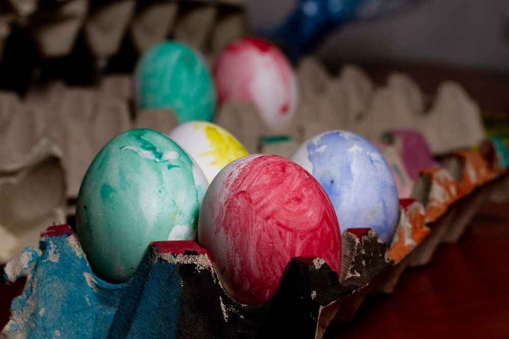 Set of painted Easter eggs in container on table