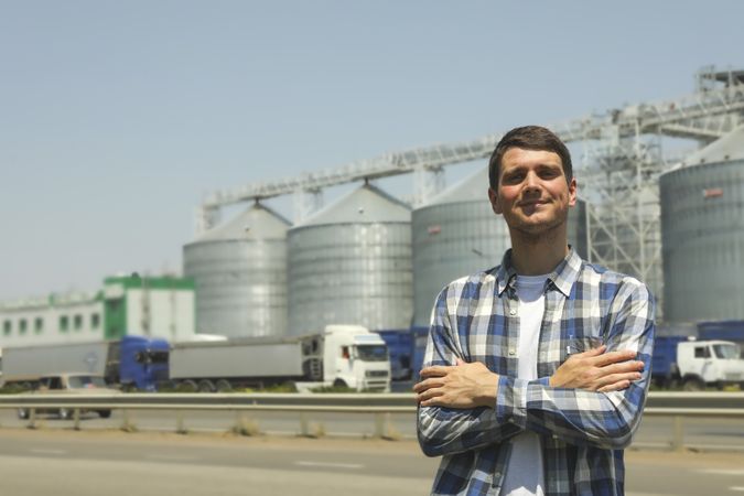Young man against grain silos. Agriculture business