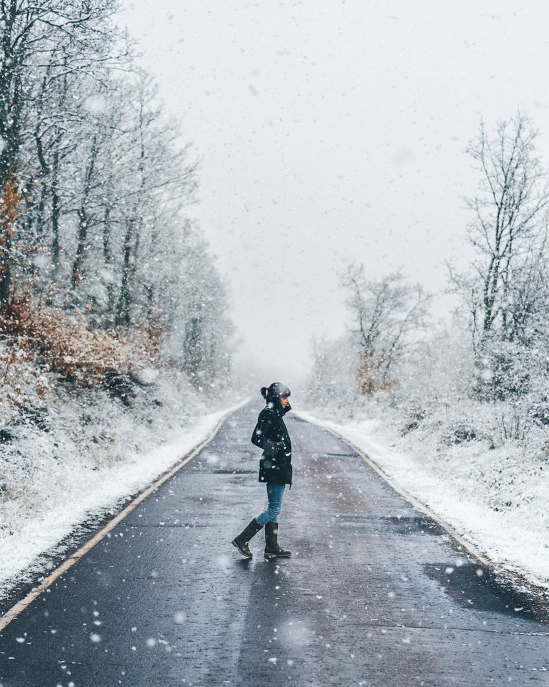 Young woman crossing winter country road