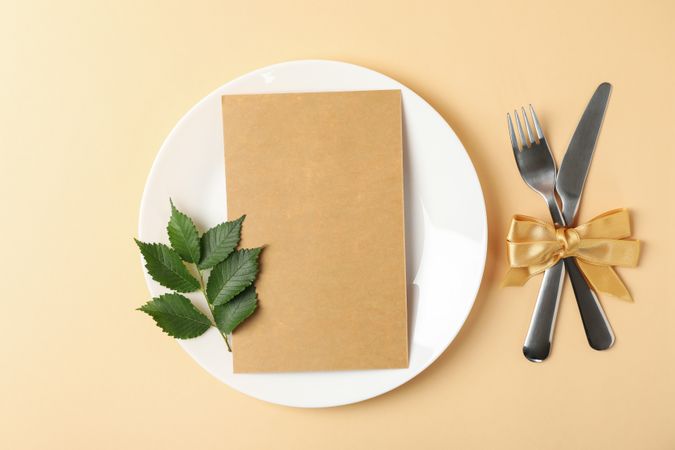 Table setting with plate, cutlery, leaf and cardboard with space for text
