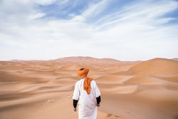 Man in turban walking among sand dunes