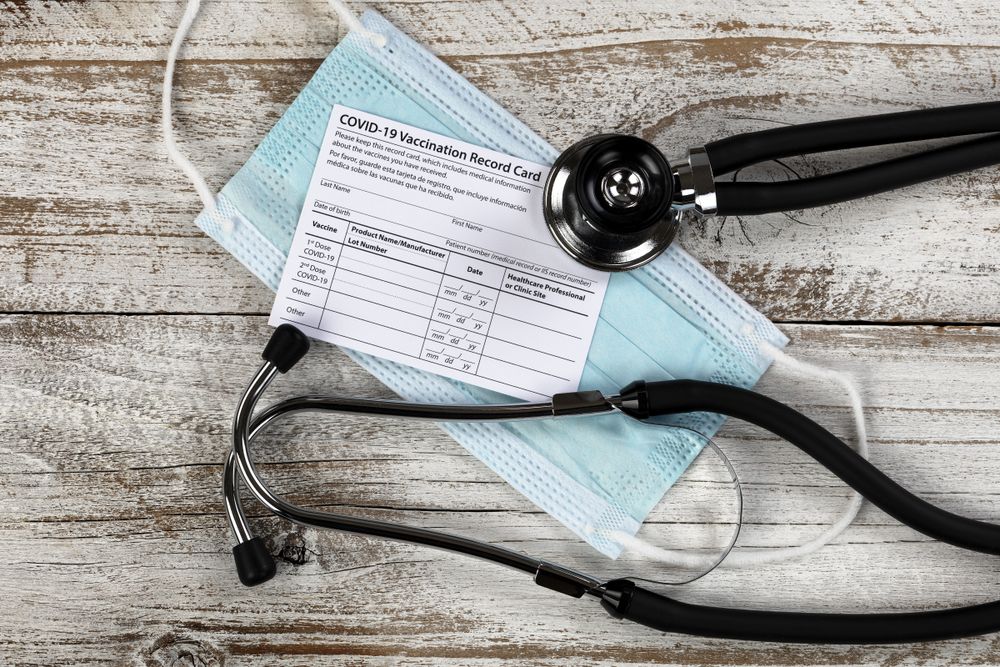 Covid 19 vaccination record card with stethoscope and facemask
