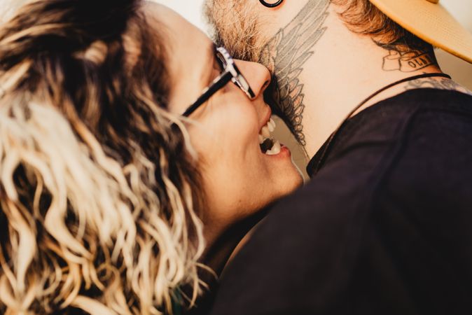 Happy couple hugging and kissing near tree in park
