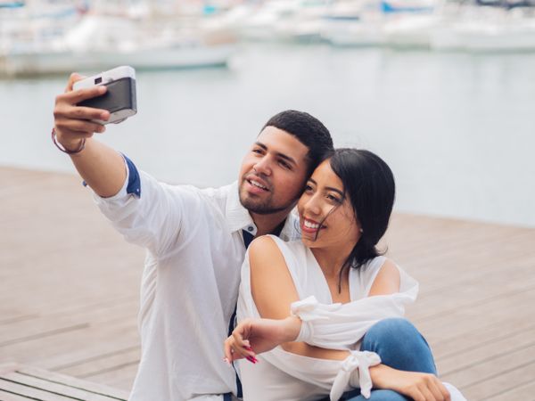 Woman with man taking photo selfie and kissing on bench