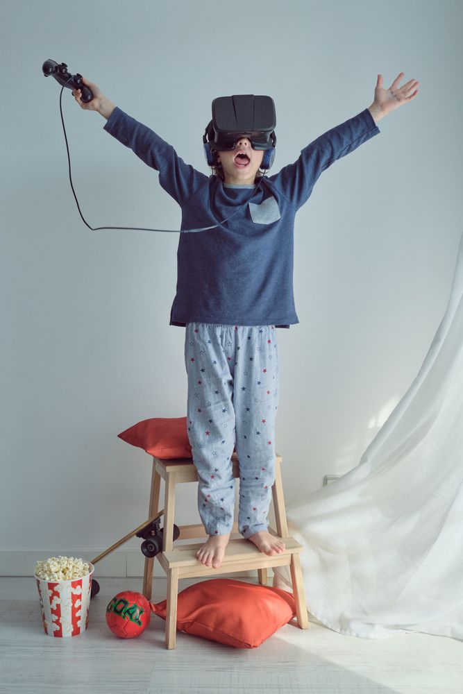 Excited boy playing game in VR goggles