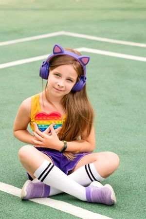 School girl sitting on court with colorful toy