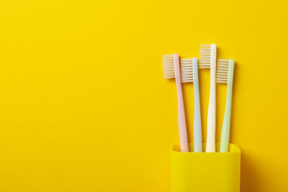 Toothbrushes on yellow background, space for text