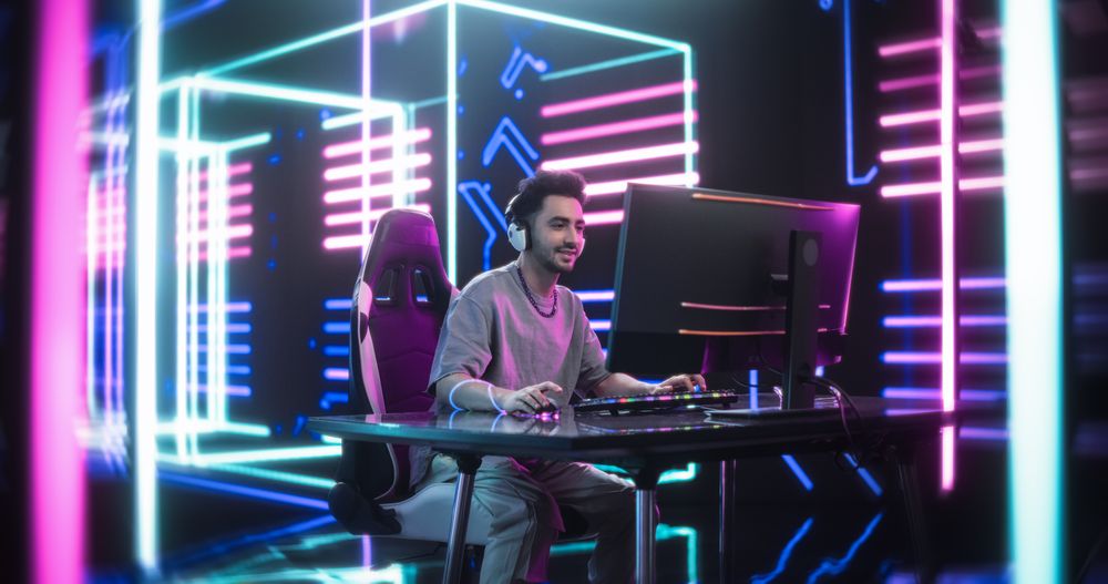Young Man Wearing Casual Comfortable Clothes and a Chain, Playing Video Games on a Desktop Computer.