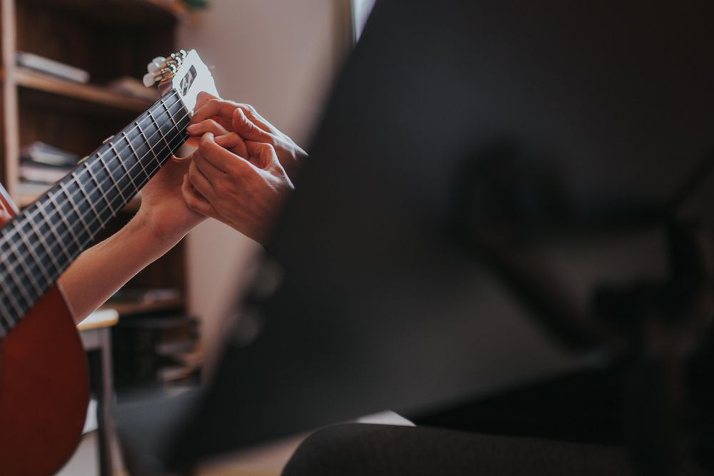 Close up of teacher helping student place fingers on correct notes of guitar